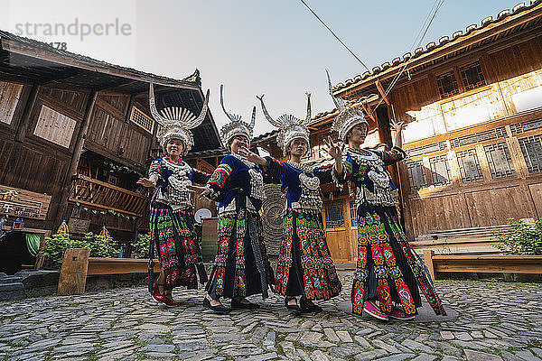 China  Guizhou  Miao women wearing traditional dresses and headdresses posing on village square