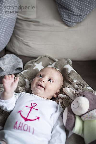 Portrait of smiling baby girl lying on a couch
