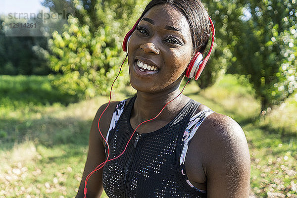 Young athlete in nature  listening music with headphones