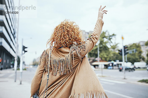 Redheaded woman hailing a taxi in the street
