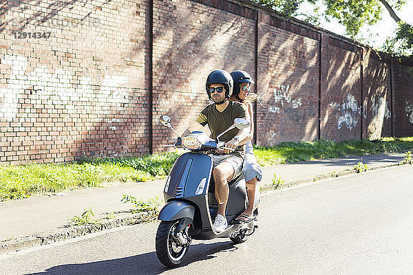 Couple riding motor scooter in summer