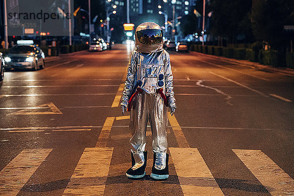 Spaceman standing on a street in the city at night