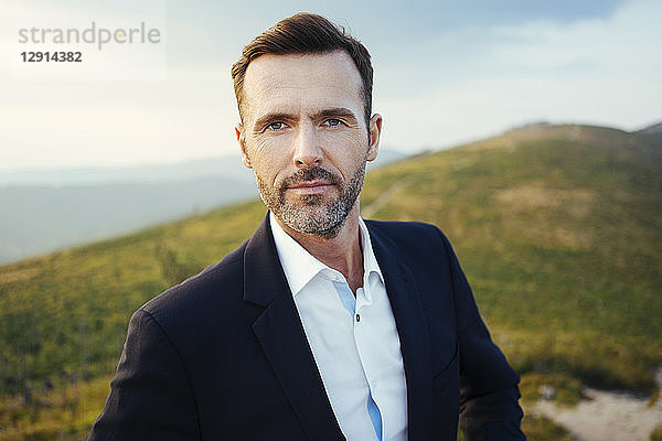 Portrait of self-confident businessman on top of a mountain