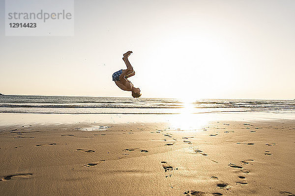 Young man doing somersaults on the beach