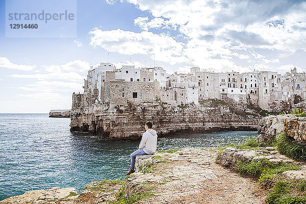 Italy  Puglia  Polognano a Mare  back view of man relaxing on rocks looking at horizon