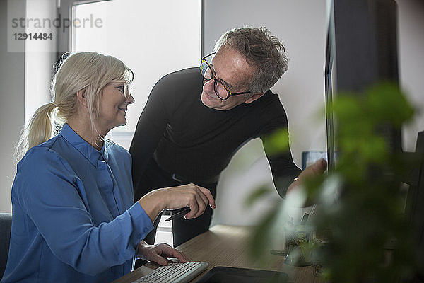 Two senior colleagues working together at desk in office