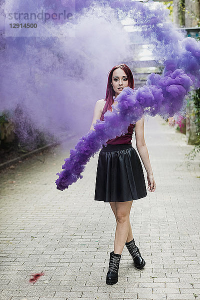 Young woman holding smoke torch outdoors