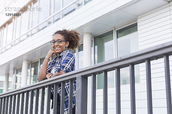 Portrait of smiling young woman leaning on railing