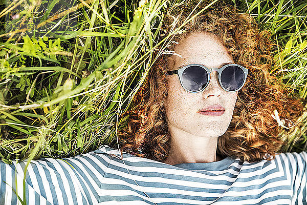 Portrait of young woman relaxing on a meadow wearing sunglasses