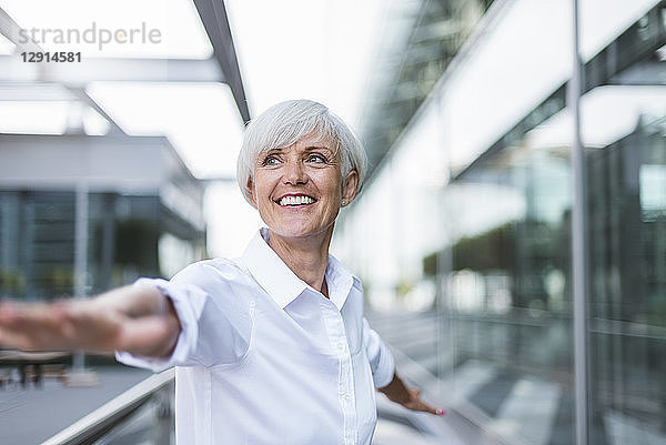 Happy senior woman in the city with outstretched arms