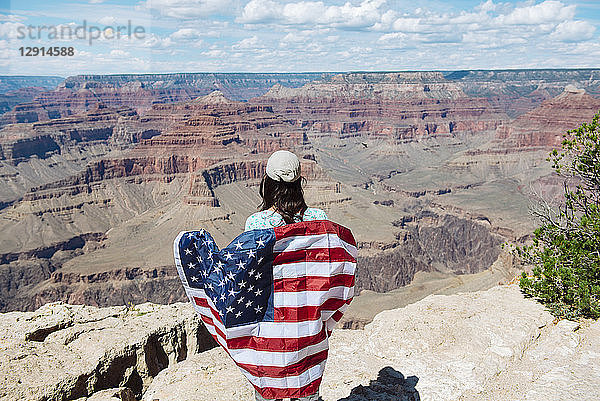 USA  Arizona  smiling woman with American flag at Grand Canyon National Park  rear view