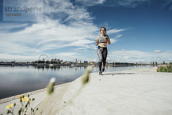 Young athletic woman running at the riverside