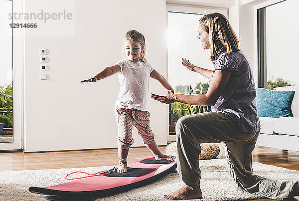 Mother and daughter exercising with surfboard in living room