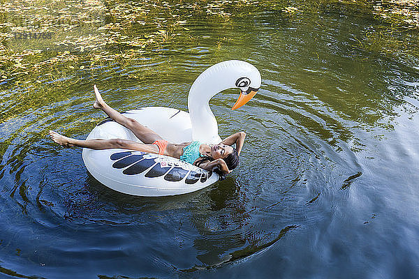 Girl floating in water on inflatable pool toy in swan shape