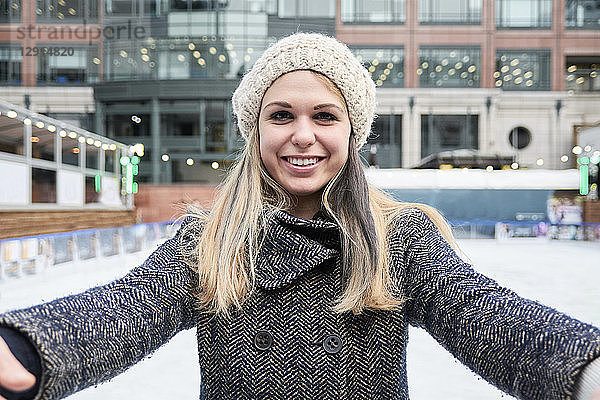 Blond young woman looking at the camera while skiing on an ice rink