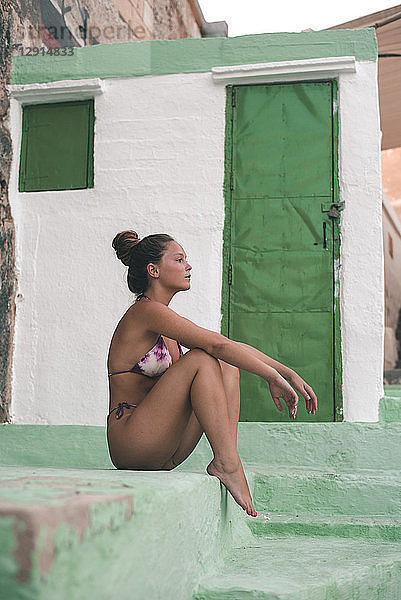 Teenage girl in sexy bikini  sitting on steps
