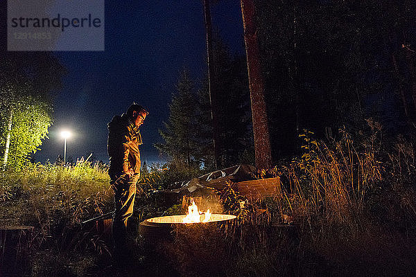 Finland  Man warming up at a camp fire on a camping ground