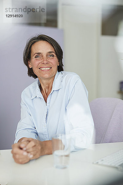 Portrait of smiling mature businesswoman sitting at desk