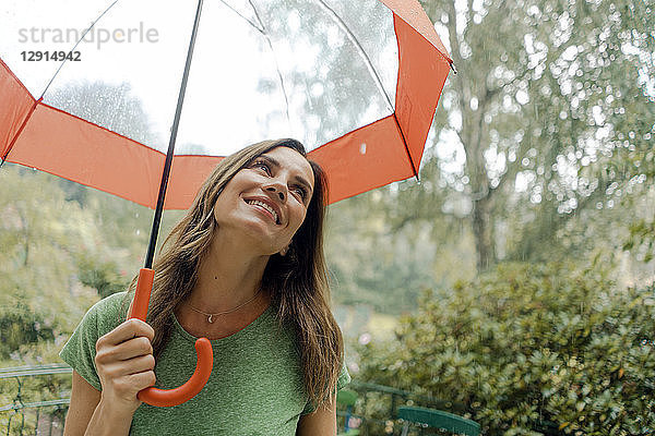 Smiling mature woman standing in rain under umbrella