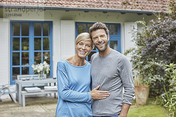 Portrait of smiling couple standing in front of their home