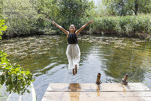 Carefree girl jumping into pond