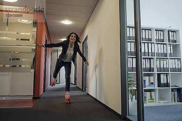 Mature businesswoman rollerskating in office corridor