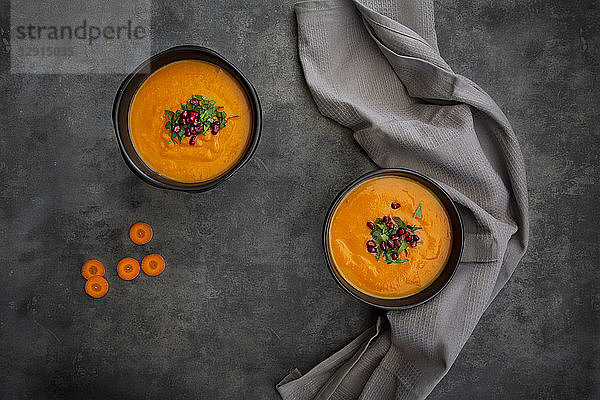 Bowl of carrot ginger coconut soup with topping of parsley and pomegranate seed