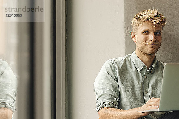 Young man using laptop  smiling