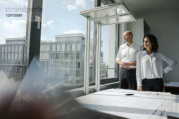 Two architects standing in office  looking out of window