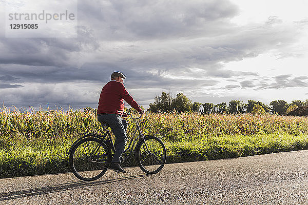 Senior man riding bicycle on country lane