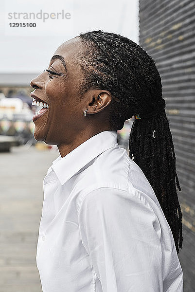 Profile of laughing businesswoman with dreadlocks wearing white shirt