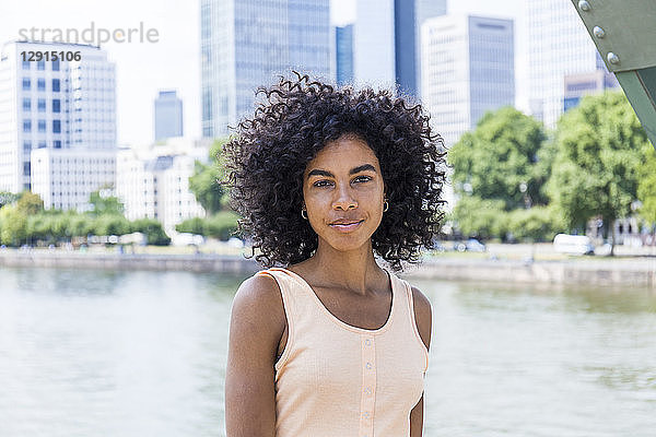 Germany  Frankfurt  portrait of relaxed young woman with curly hair in front of Main River