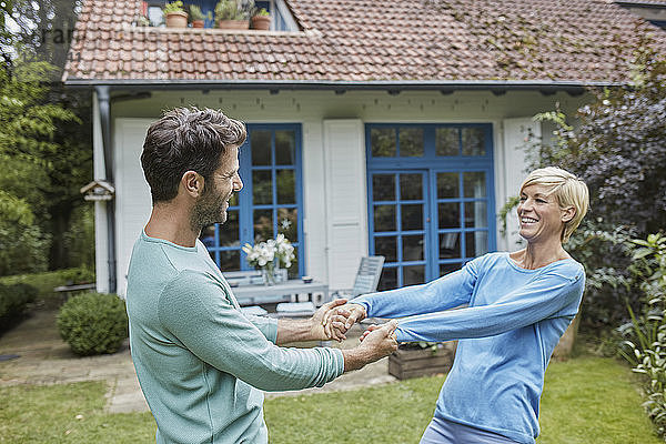 Happy couple dancing in front of their home