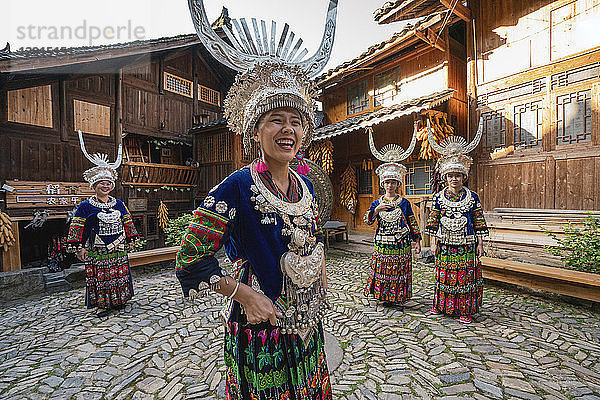 China  Guizhou  happy Miao women wearing traditional dresses and headdresses standing on village square