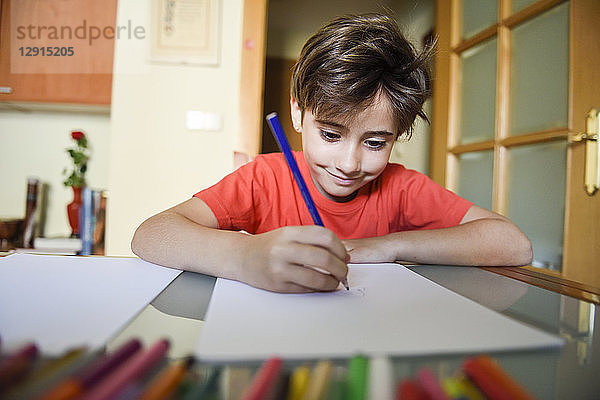 Portrait of smiling little girl drawing with coloured pencils at home