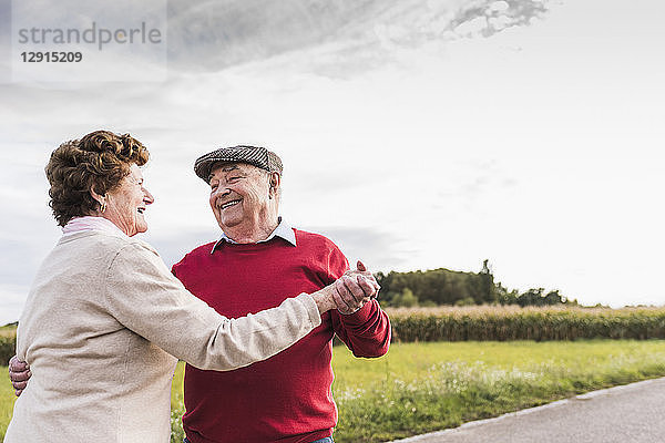 Happy senior couple dancing on country road