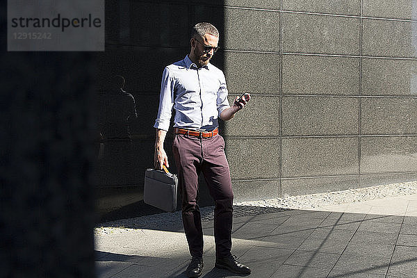 Businessman using cell phone outdoors