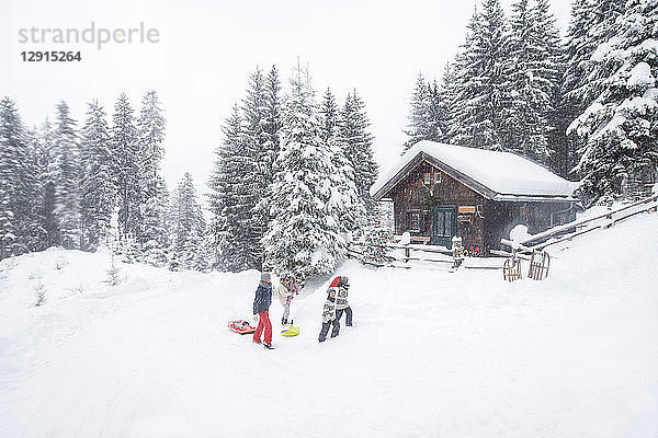 Austria  Altenmarkt-Zauchensee  family with sledges at wooden house at Christmas time