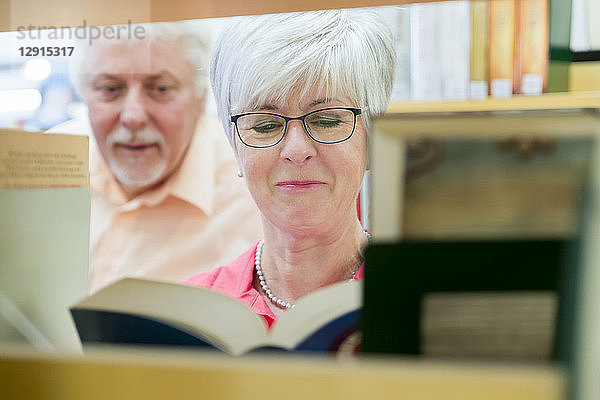 Portrait of smiling senior woman with book in a city library