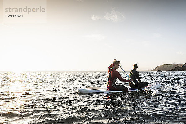Couple on paddling on paddleboard at sunset on the sea