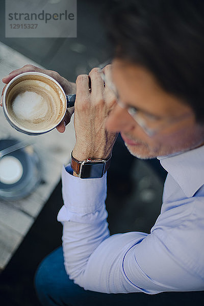 Mature businessman sitting in coffee shop  wearing smart watch