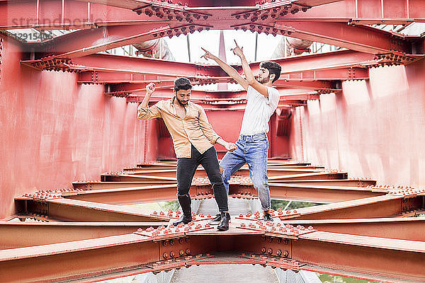 Young gay couple dancing on steel girders of a footbridge