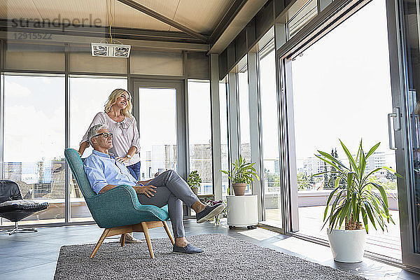 Mature couple relaxing at home looking out of window