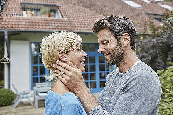 Happy affectionate couple in front of their home