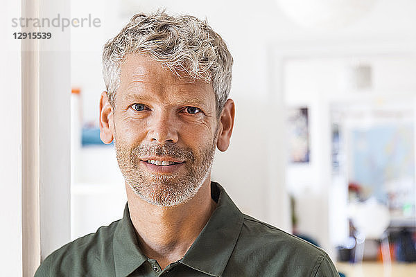 Portrait of smiling mature man with grey hair and stubble at home