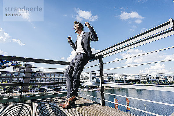 Happy businessman standing on balcony  with arms out