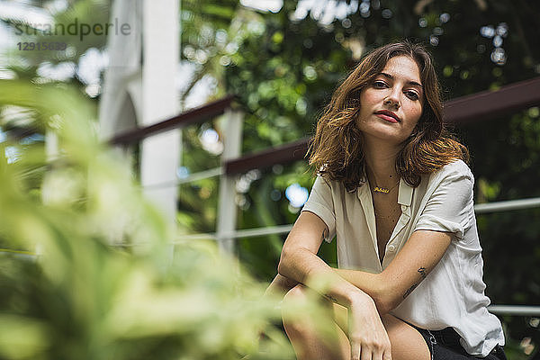Young woman sitting in greenhouse  portrait