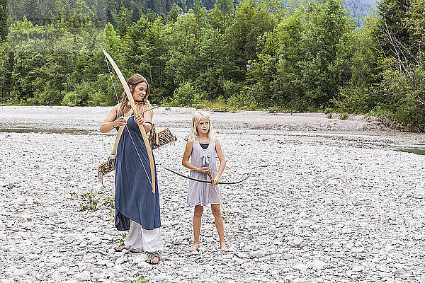 Mother and daughter with bow and arrow in the nature