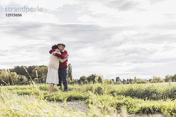 Senior couple hugging in rural landscape