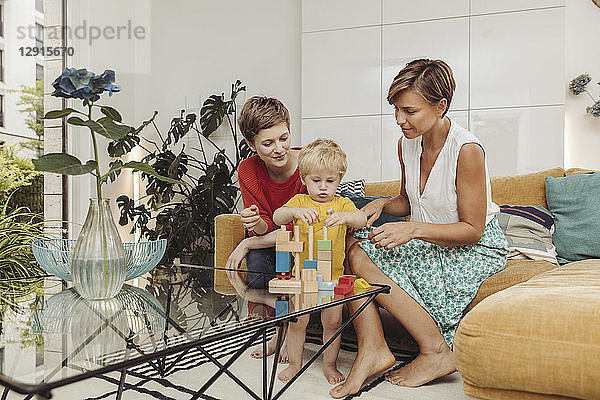 Two mothers learning and playing with their child at home